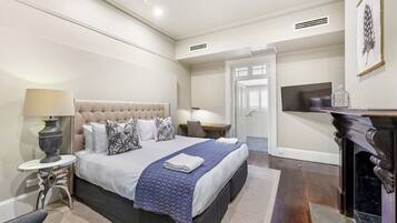 A modern bedroom with a large bed, bedside tables, a TV, and a fireplace.