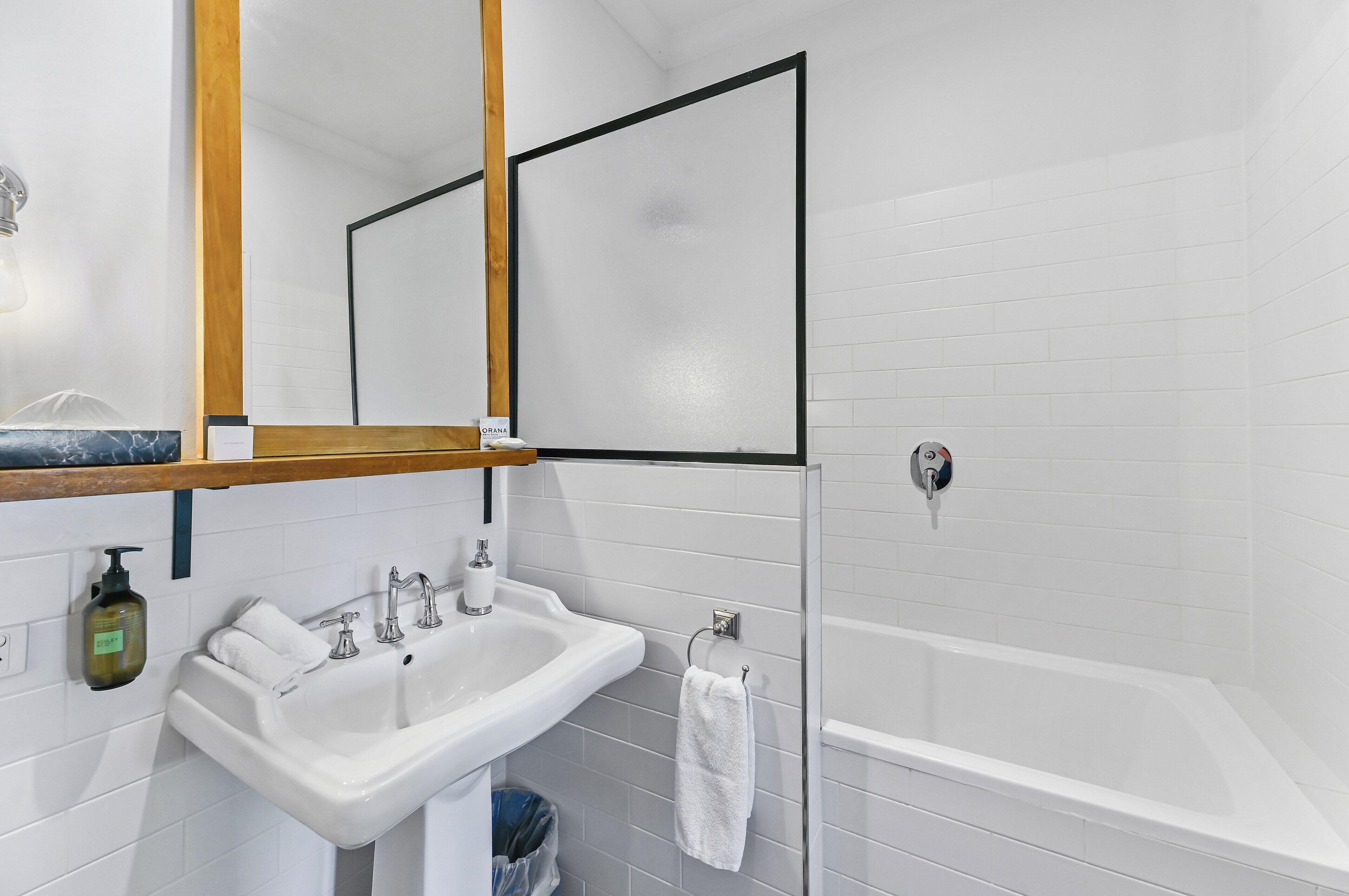 A bathroom with a white sink, mirror, and bathtub.