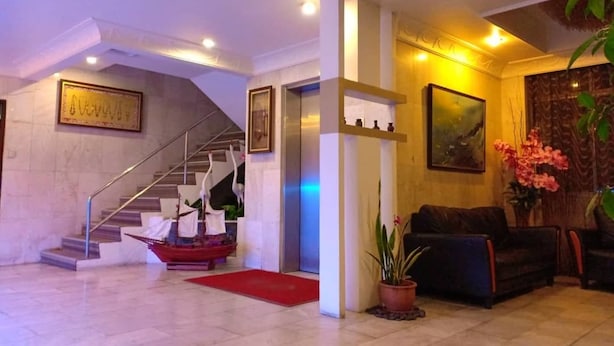 Un hall con escalera, una recepción, un sofá y una planta en maceta.