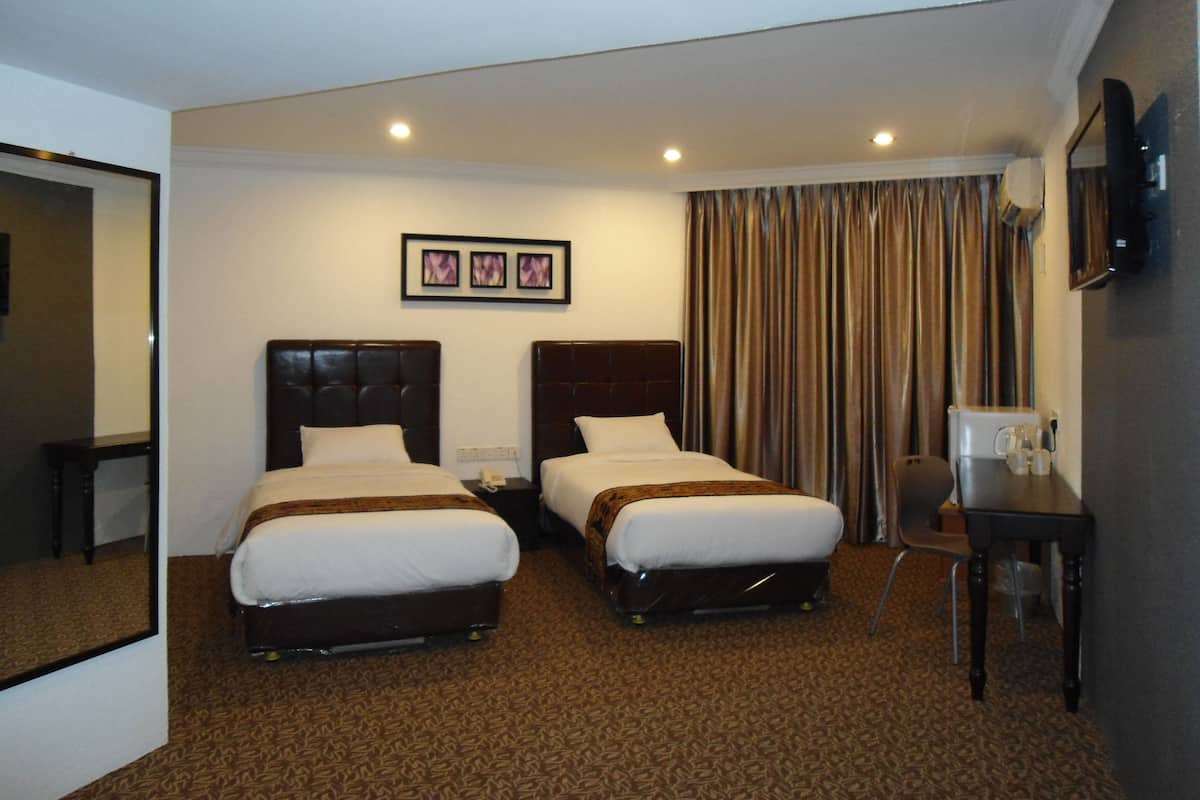 Habitación de hotel con dos camas, un escritorio, una silla, cafetera y televisor en la pared.