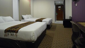 Habitación de hotel con dos camas, un escritorio y un televisor en la pared.