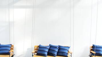 Three wooden swings suspended from a black metal frame against a white wall.
