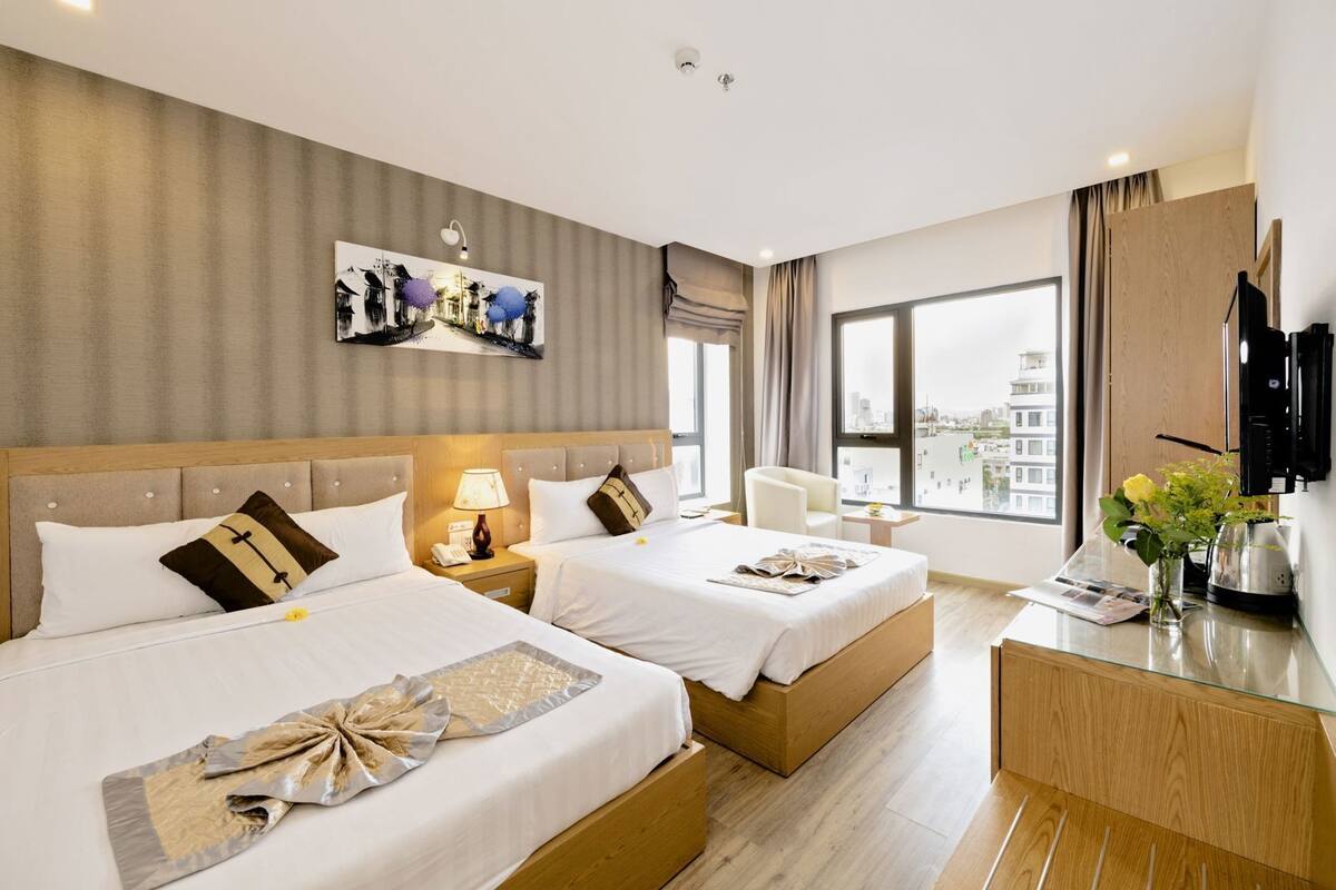 Habitación de hotel con dos camas, un ventanal grande, televisor de pantalla plana y vista a la ciudad.