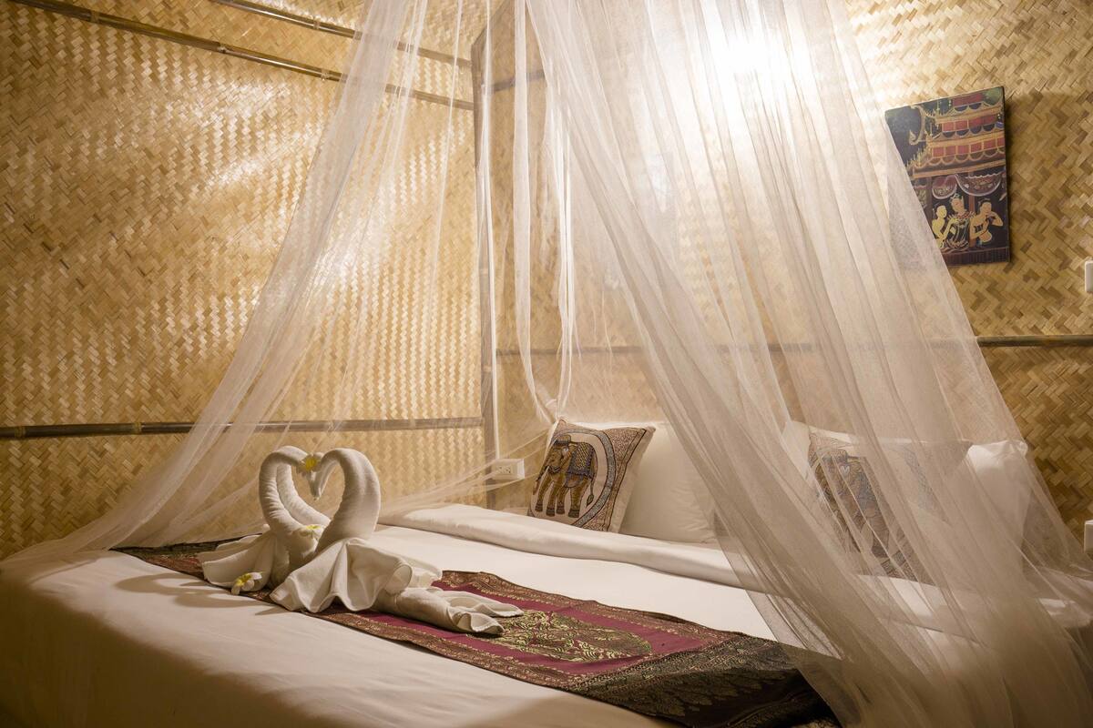 A bed with a canopy, decorative pillows, and a wall with a woven pattern.