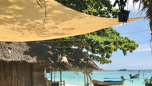 A beachside café with wooden furniture and a thatched roof, overlooking the sea with boats. - Forra Diving Resort - Pattaya Beach - Koh Lipe (Koh Lipe)