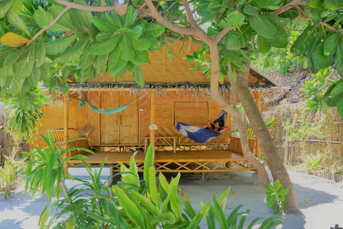 A wooden structure with a thatched roof, a hammock, and a wooden bench.