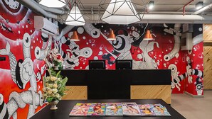 A reception area with a vibrant mural, a black reception desk, and a table with magazines. - Sunshine Hip Hotel (Pattaya)