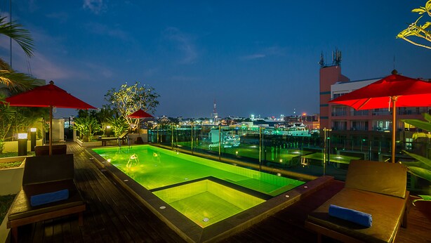 A rooftop pool area with lounge chairs and umbrellas, surrounded by glass railings and city views. - Sunshine Hip Hotel (Pattaya)