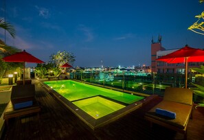 A rooftop pool area with lounge chairs and umbrellas, surrounded by glass railings and city views. - Sunshine Hip Hotel (Pattaya)