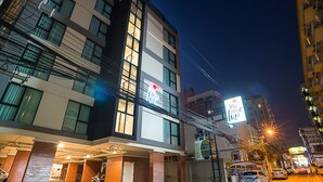 A multi-story hotel with a modern design, featuring a prominent sign for a restaurant and a visible entrance with a covered area. - Sunshine Hip Hotel (Pattaya)