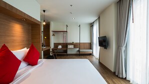 A modern hotel room with a large bed, a desk, a chair, a TV, and a bathroom area. - Sunshine Hip Hotel (Pattaya)
