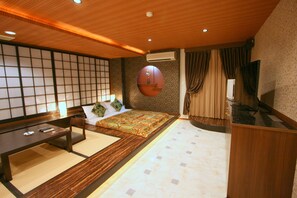 A traditional Japanese-style bedroom with tatami flooring, a low wooden bed, a futon, a wooden desk, and a shoji screen. - Hotel AURA Kansai Airport - Adults Only (Sennan)