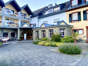 Une cour avec un bâtiment en pierre, une porte en bois et un chemin pavé.