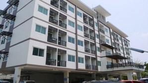 Un immeuble résidentiel à plusieurs étages, doté de balcons, d’un garage et d’un toit plat.