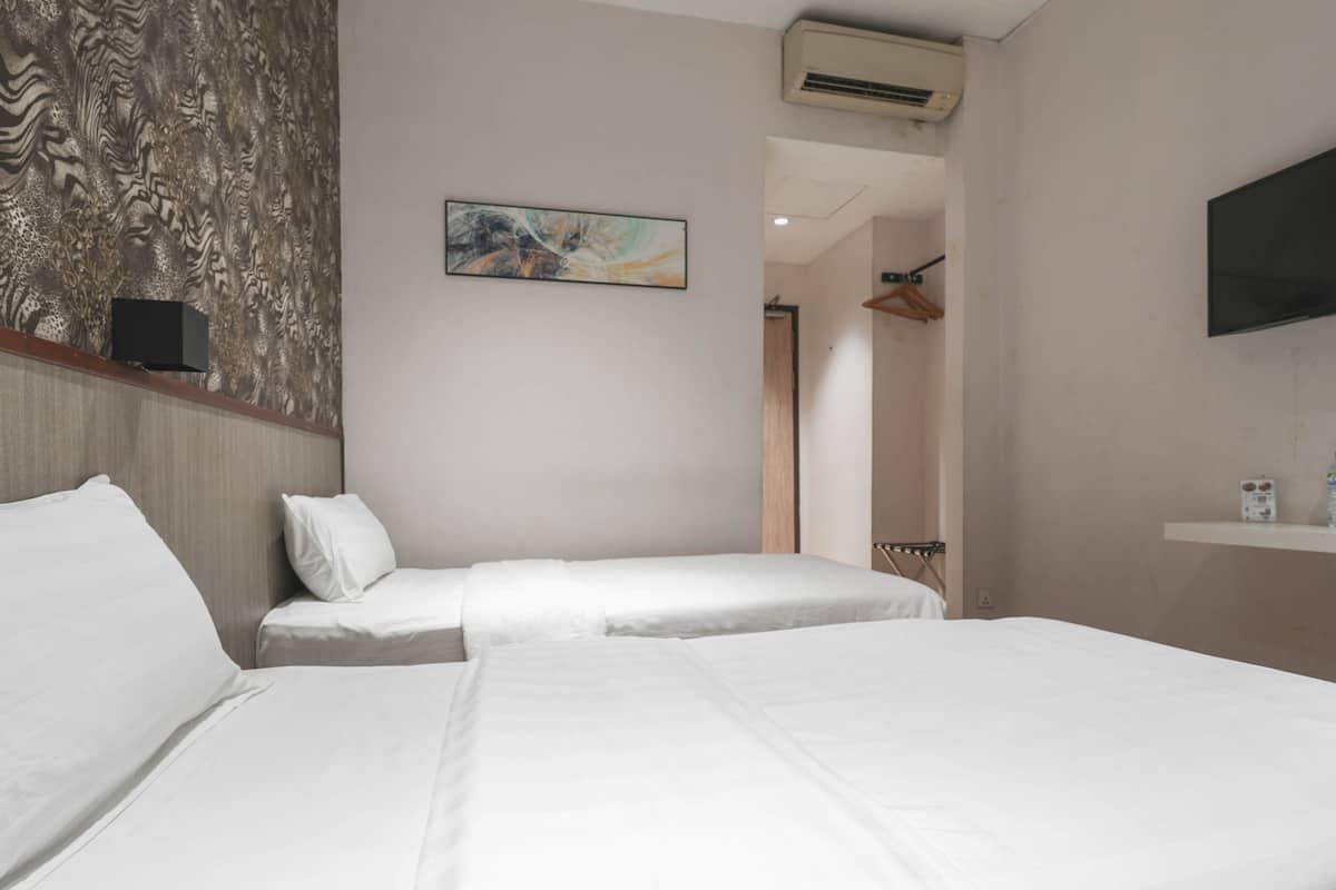 Quarto de hotel com duas camas, um quadro na parede, ar condicionado e televisão fixada na parede.