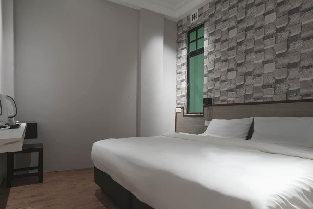 Quarto com cama, escrivaninha e janela com cortina verde.