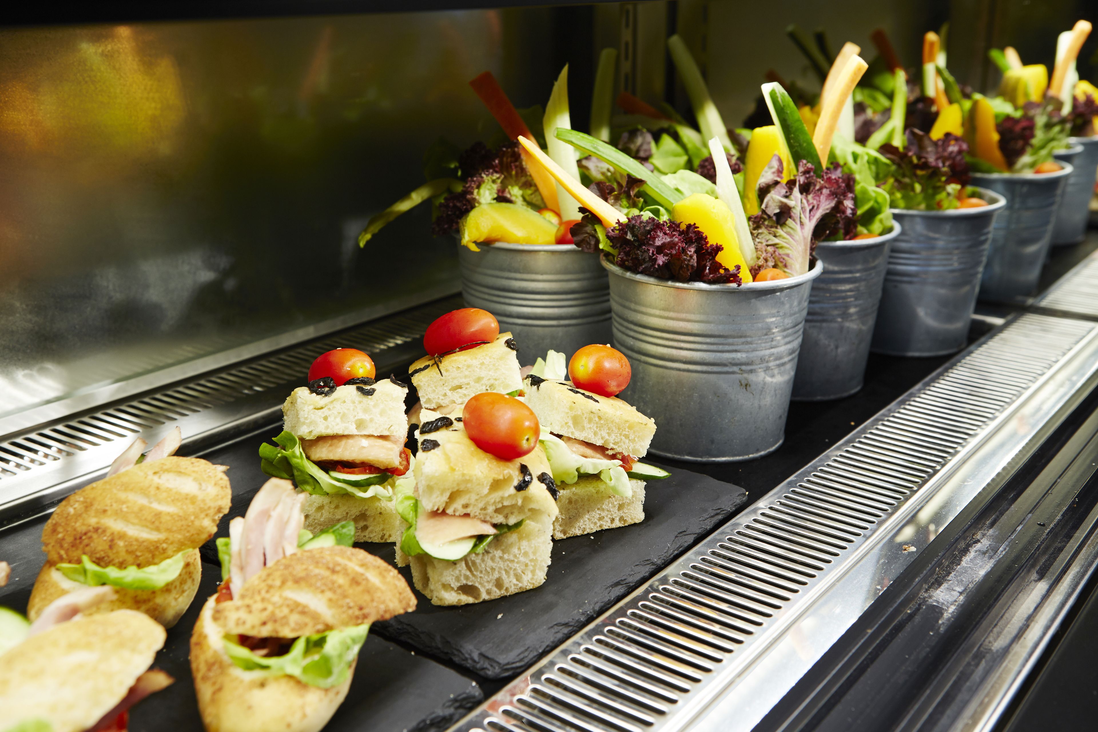Un buffet con diversi cibi, tra cui panini, insalate e frutta.
