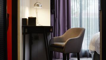 A hotel room with a desk, chair, and a bed.