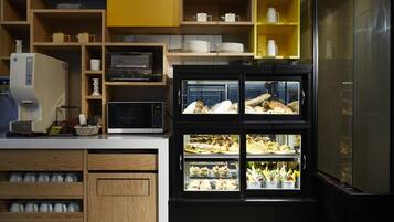 Una cocina con armarios de madera, un microondas, una cafetera y una vitrina con alimentos.