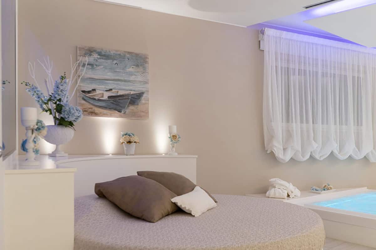 Un baño moderno con bañera, una zona de estar circular con cojines, un tocador con espejo y un cuadro en la pared.