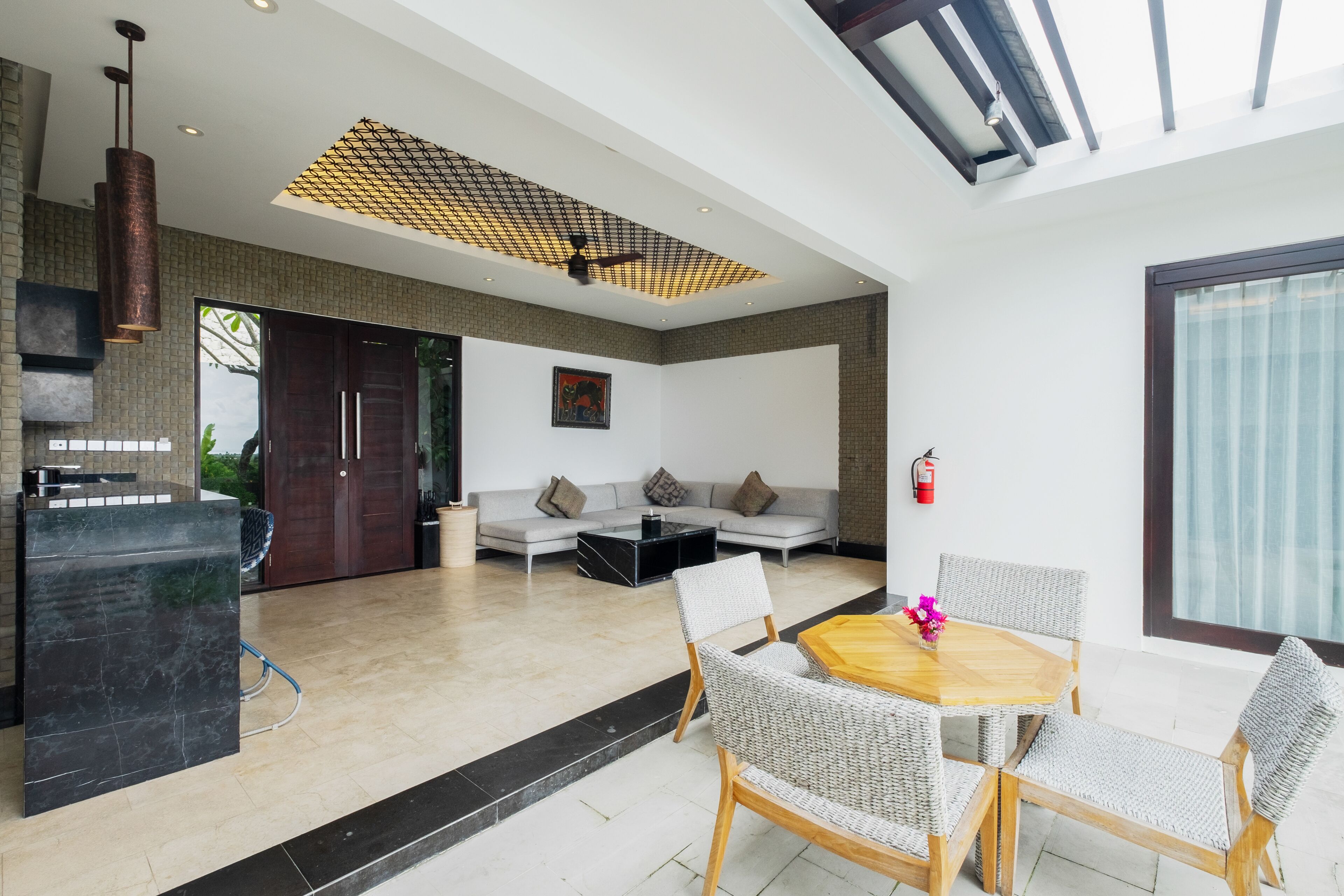 A modern living room with a sofa, coffee table, and a dining area with chairs and a table.
