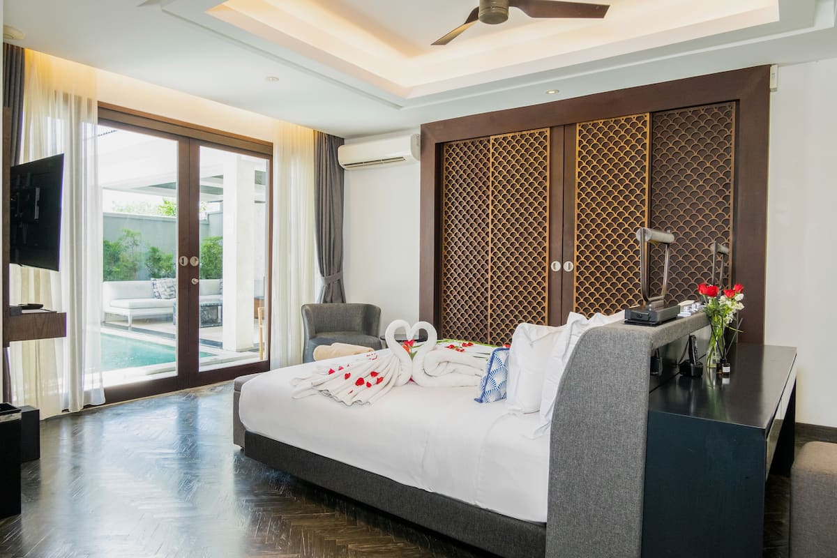Habitación de hotel con cama, escritorio, silla, televisión y vista a la piscina.