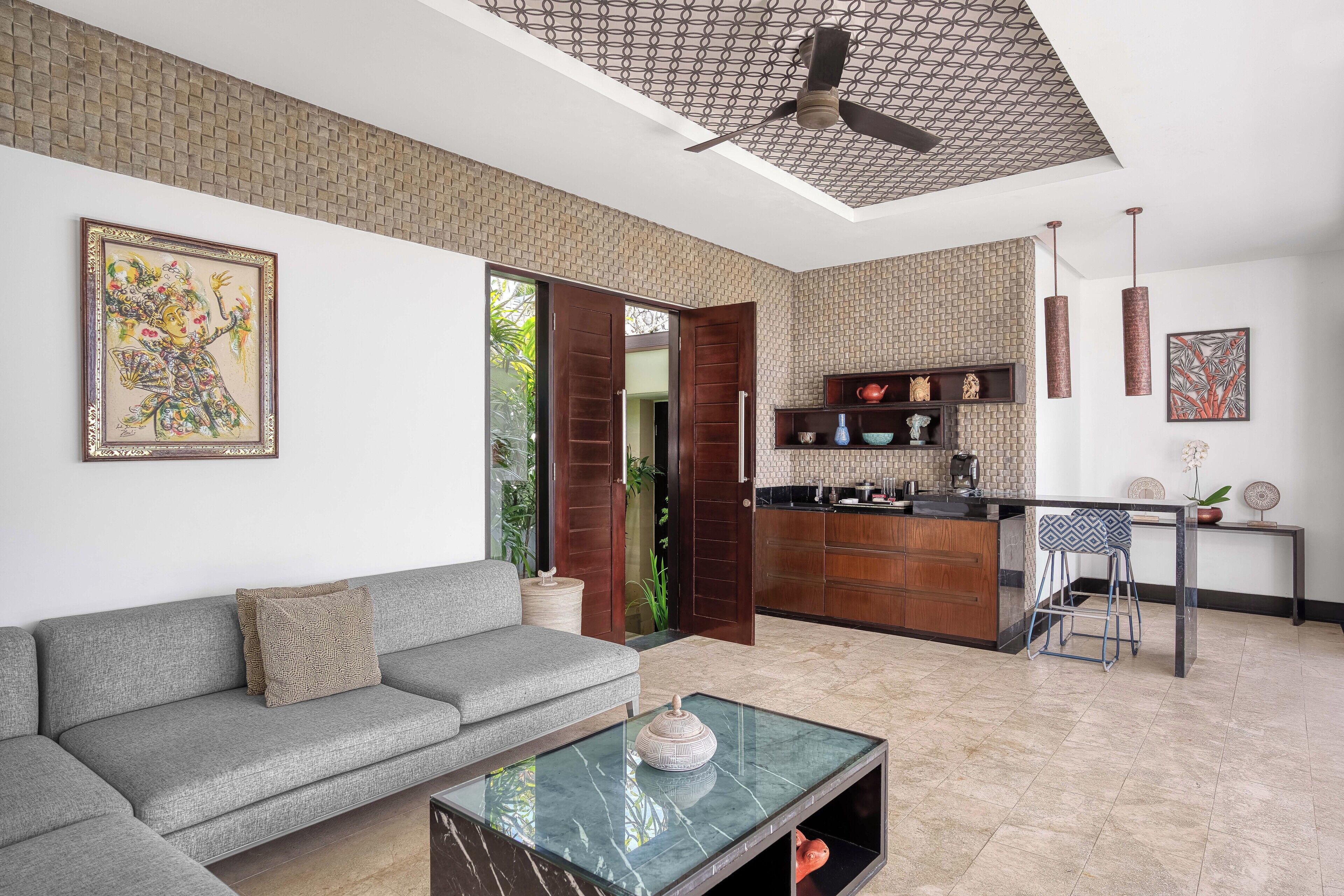A modern living room with a grey sofa, a coffee table, and a kitchen area with a bar.