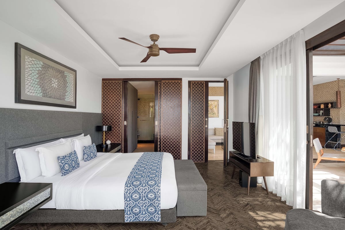 Una habitación de hotel moderna con una cama grande, un ventilador de techo y un televisor.