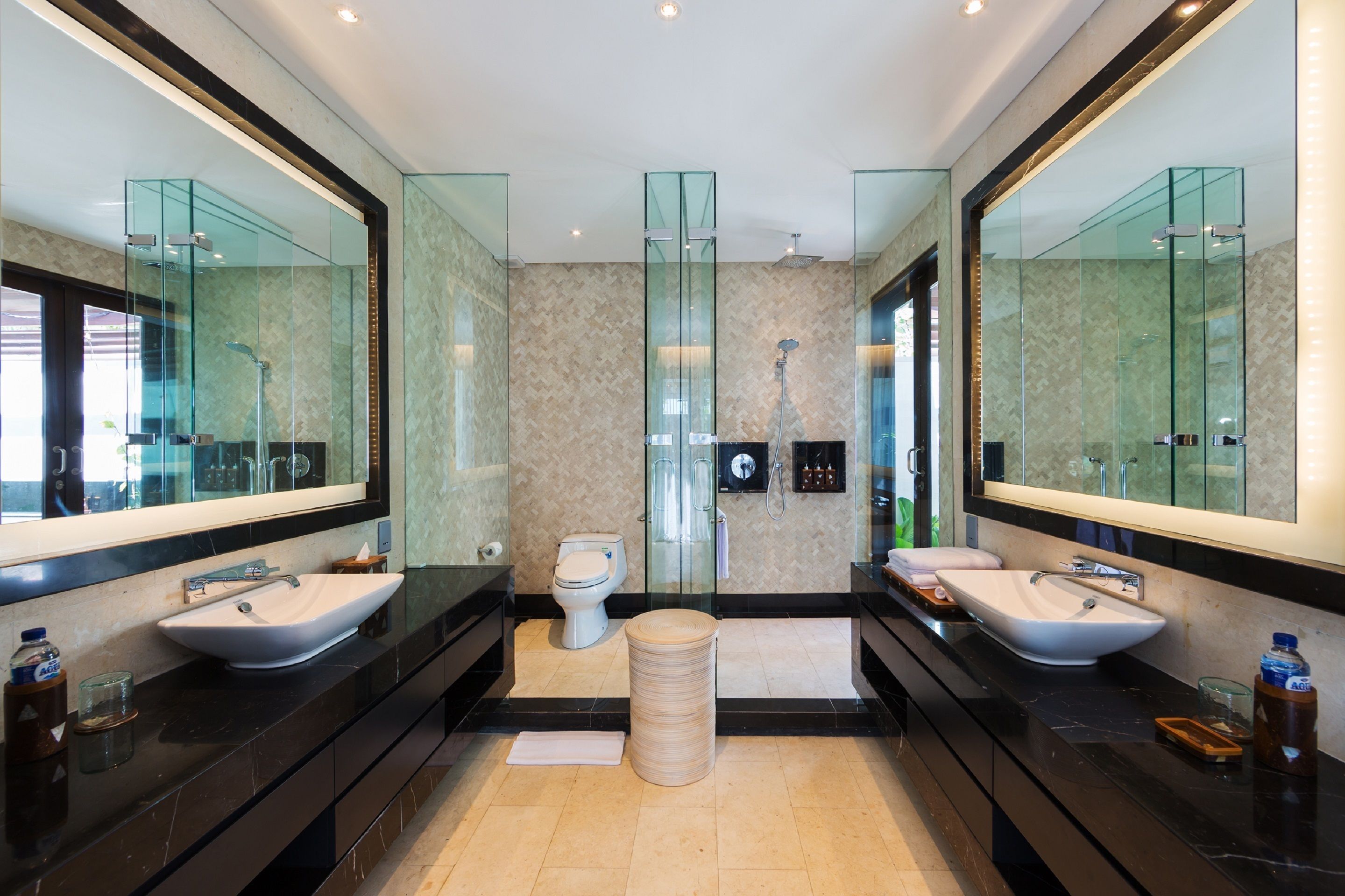 A modern bathroom with two sinks, a toilet, and a glass shower enclosure.