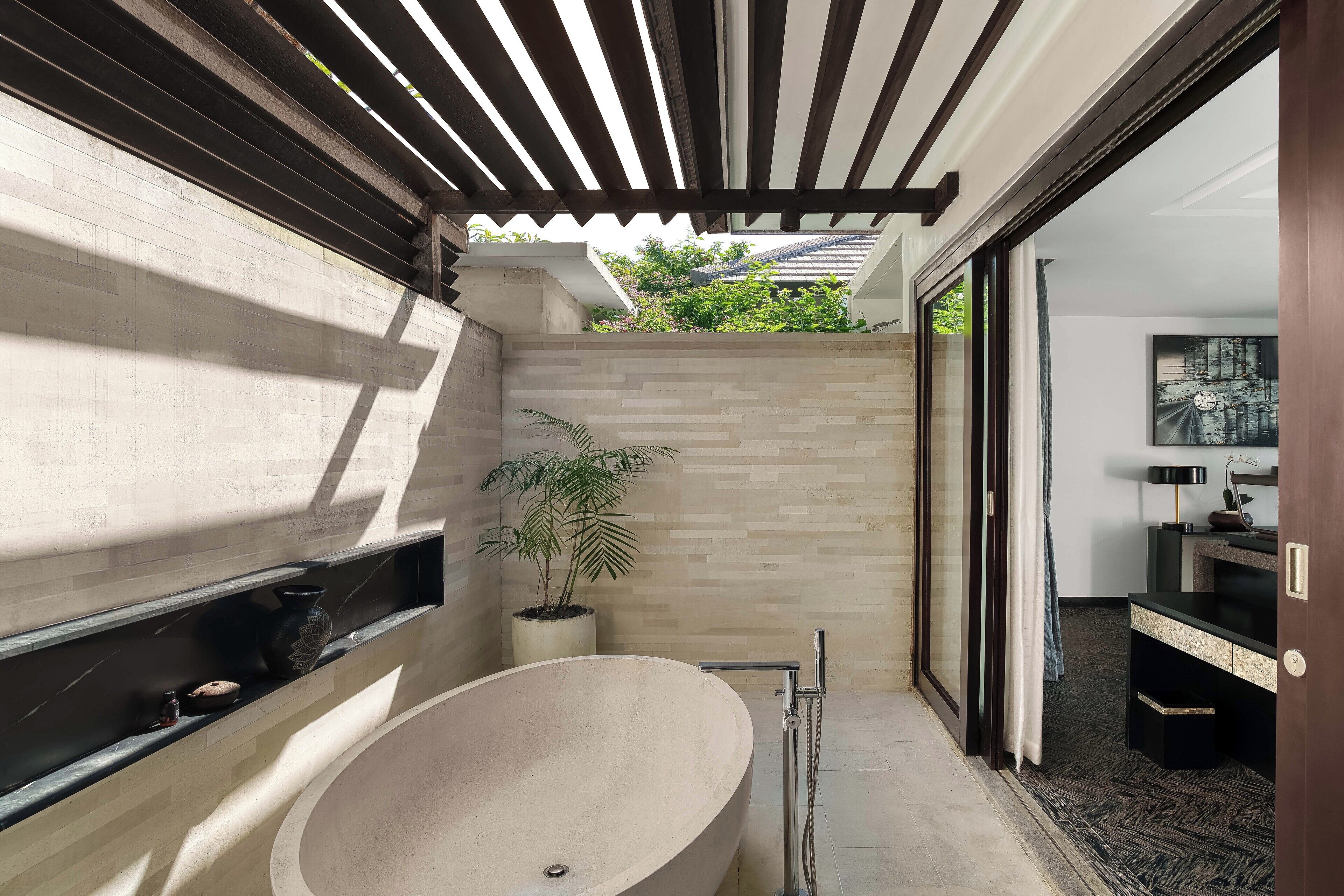 A modern bathroom with a large freestanding bathtub, a potted plant, and a shower area.
