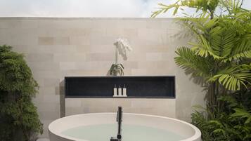 A modern bathroom with a freestanding bathtub, a marble countertop, and a potted orchid.