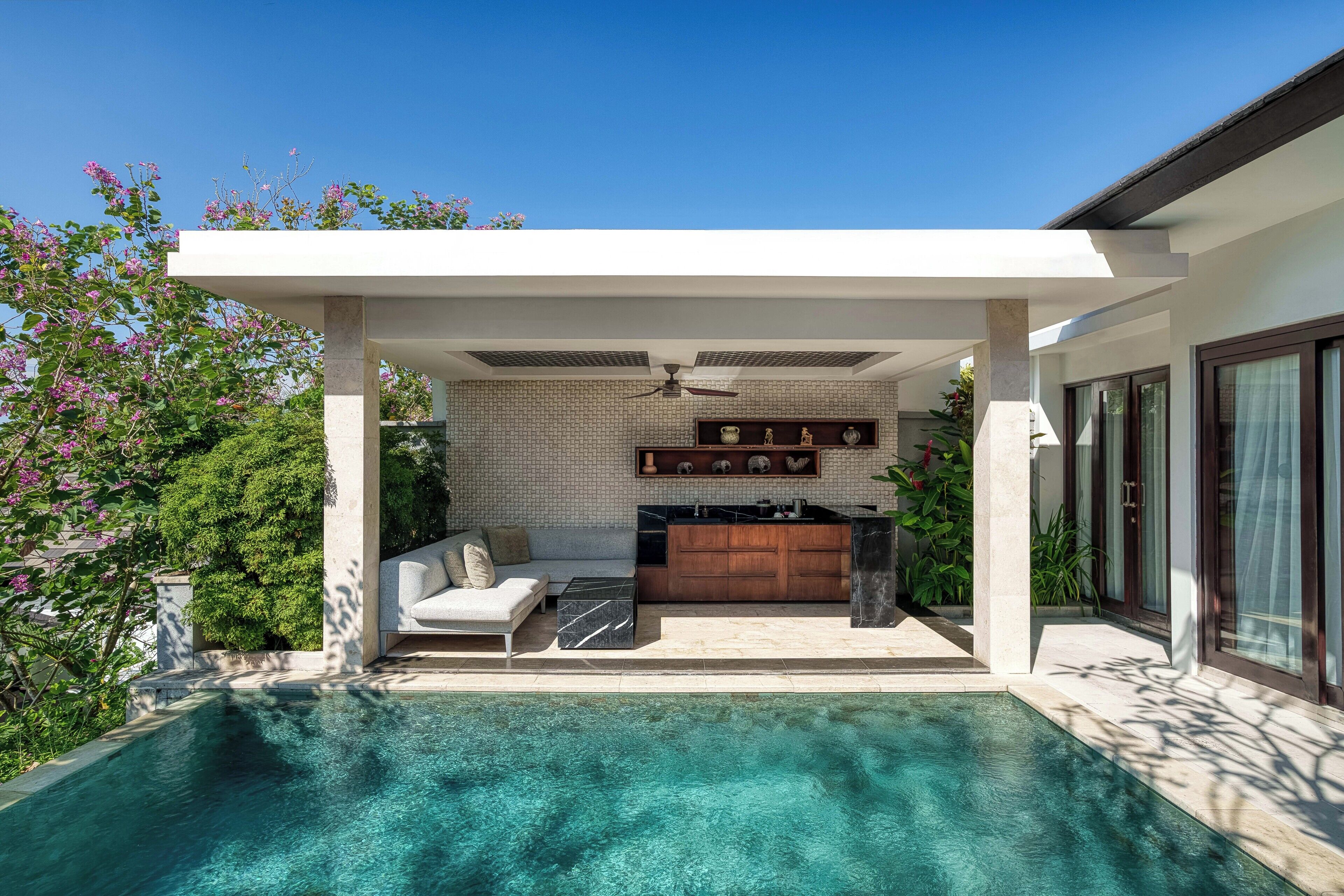 A modern outdoor pool area with a built-in kitchen and seating area.