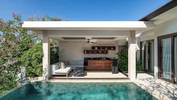 A modern outdoor pool area with a built-in kitchen and seating area.