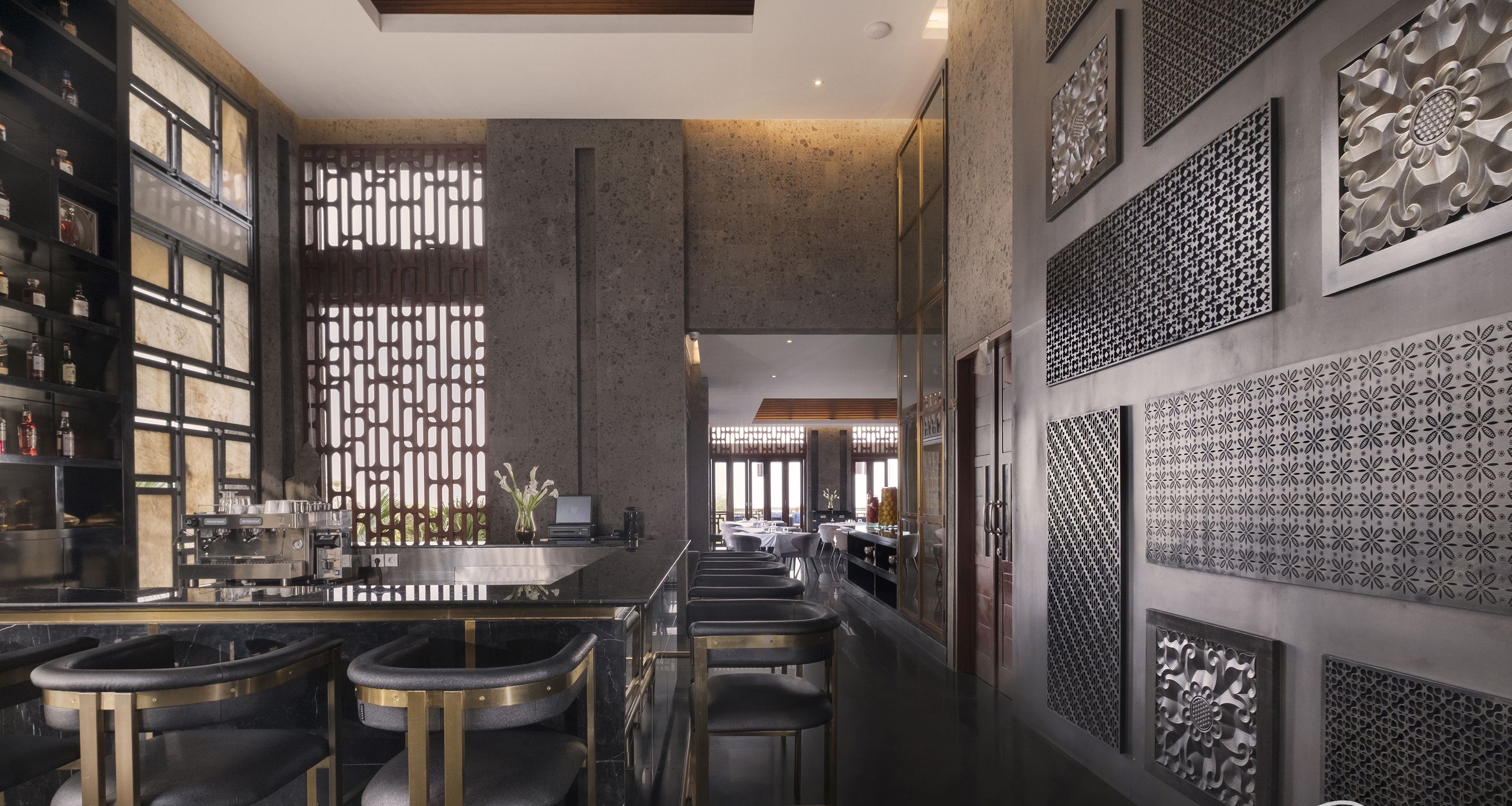 A modern bar area with a long counter, bar stools, and decorative wall panels.