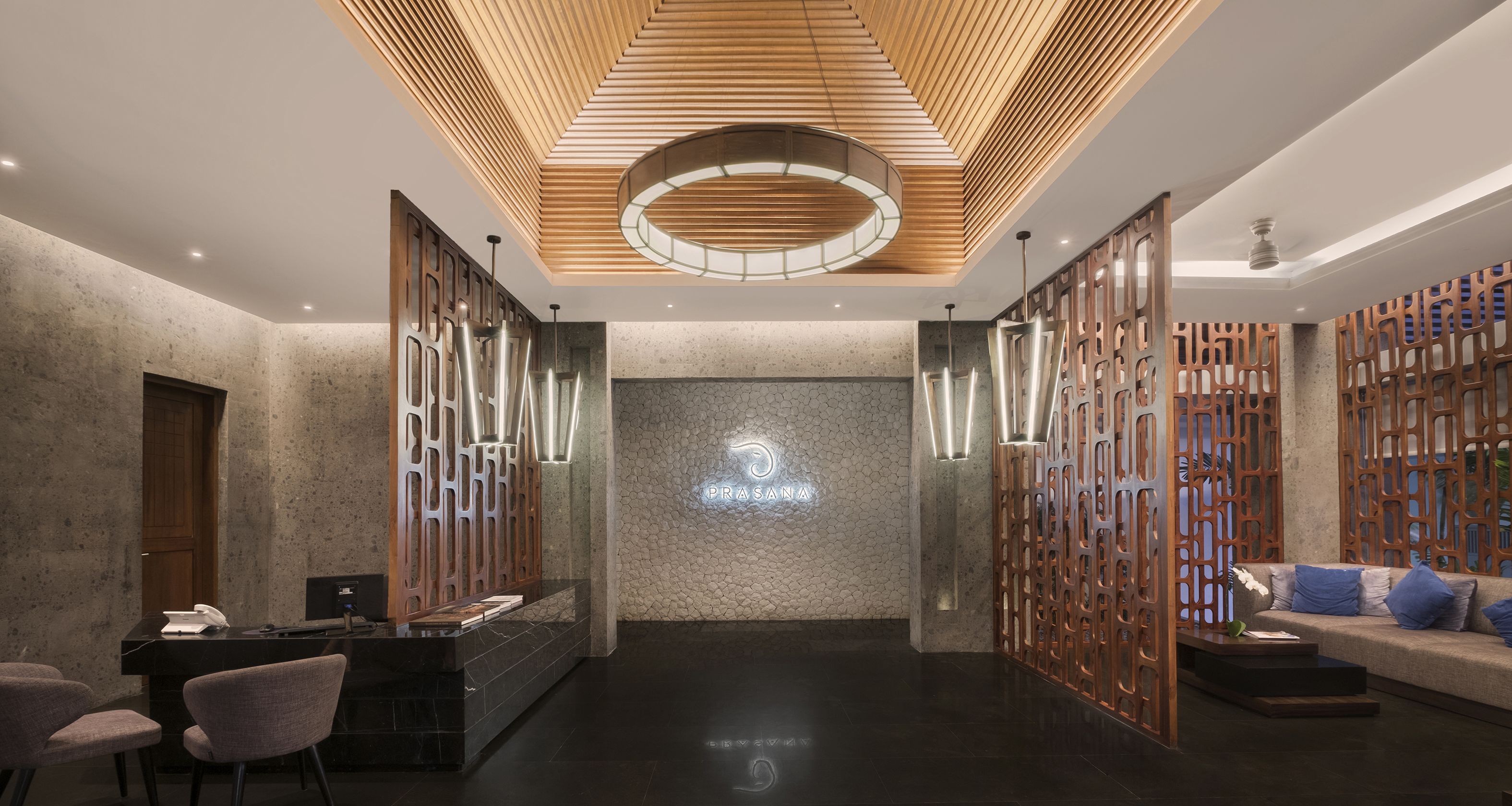 A modern reception area with a stone wall, a reception desk, and a seating area with a sofa and chairs.