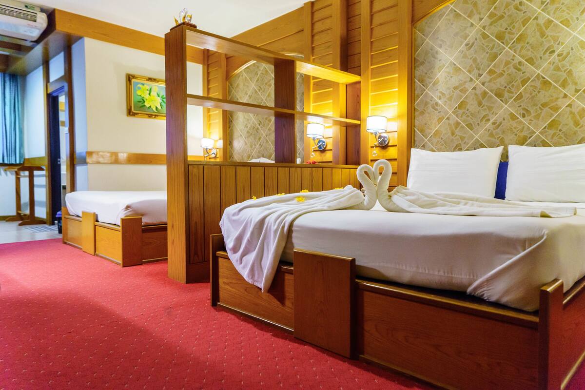 A hotel room with a wooden bed, a large mirror, and a red carpet.