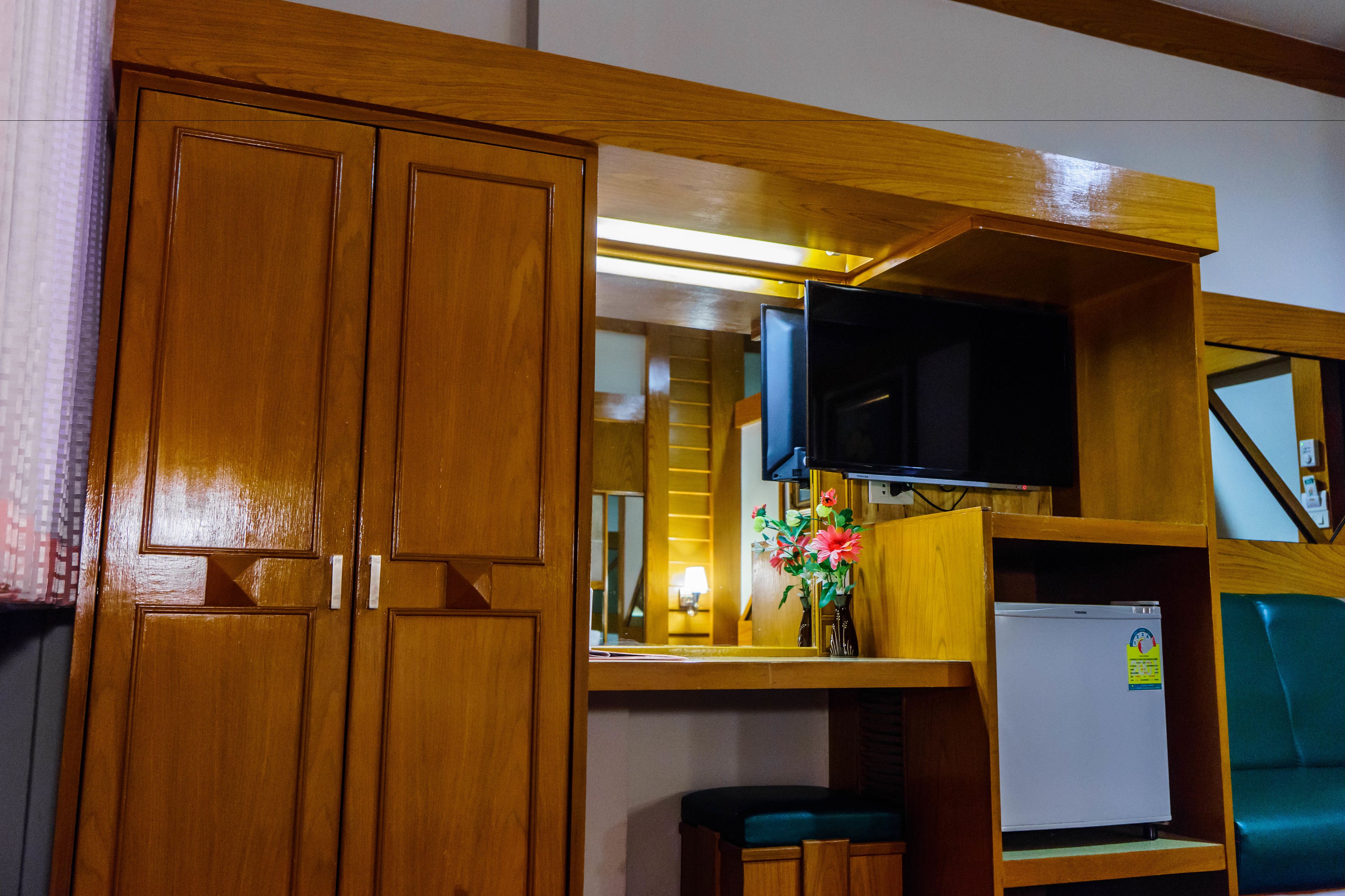Ein kompakter Raum mit Holzschnitzereien, einer kleinen Kühlbox, einem an der Wand montierten Fernseher und einer Bank.