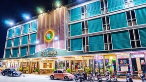 A hotel with a neon sign, multiple floors, and a row of parked motorcycles in front. - Siri Hotel (Nakhon Ratchasima)