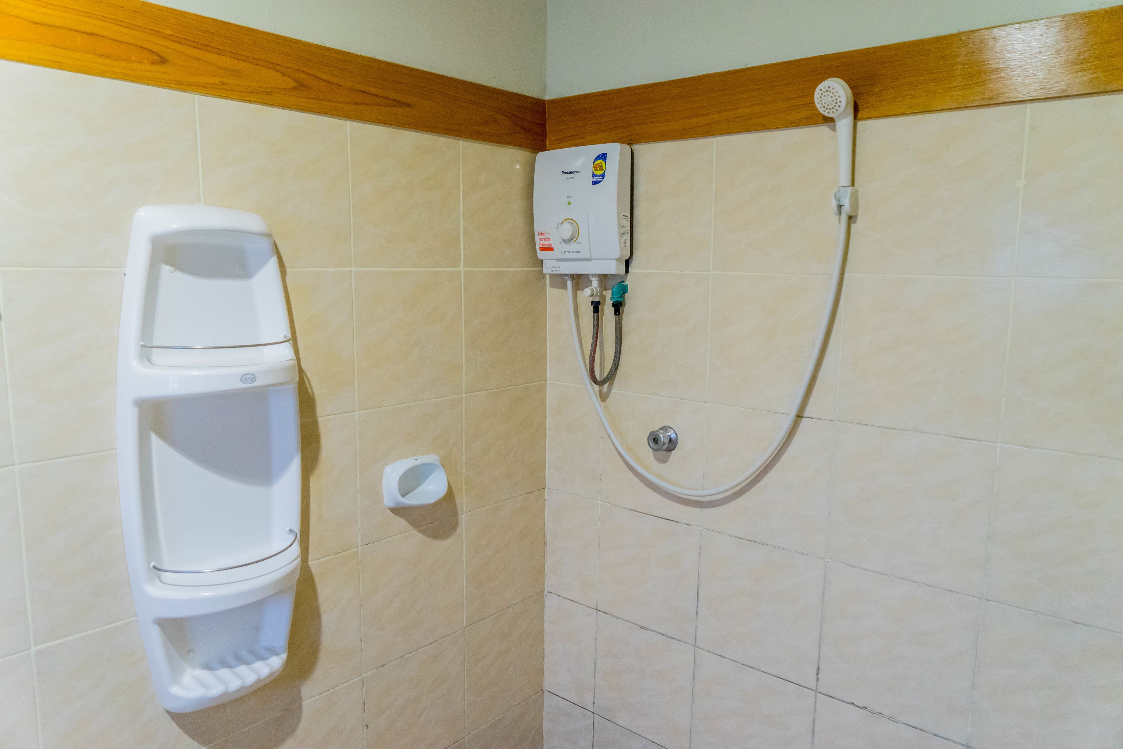 A bathroom with a toilet, a hand dryer, and a shower unit.