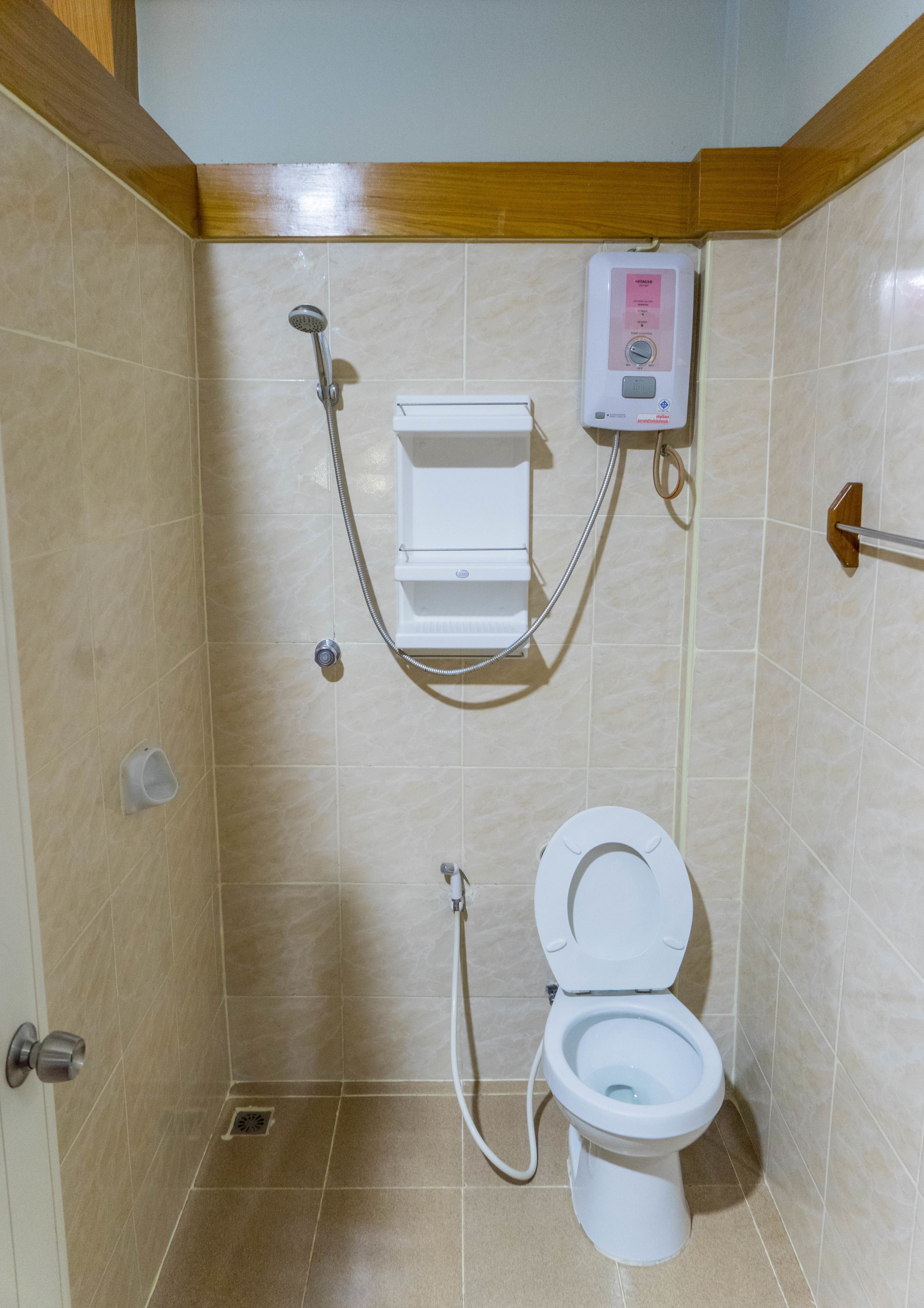 Un baño pequeño con inodoro, ducha y calentador de agua.