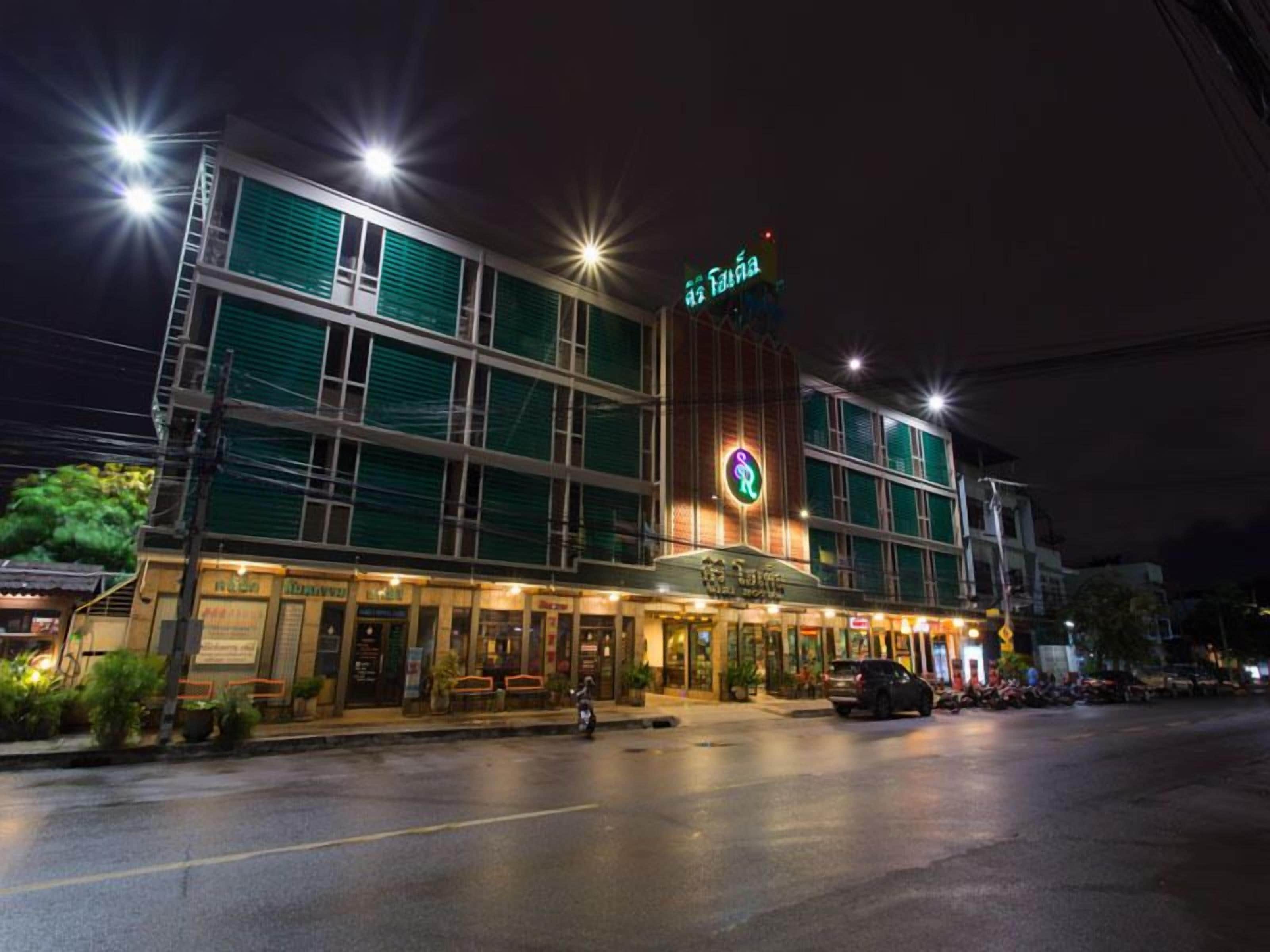 A hotel with a green facade and a sign indicating it is a 'Hotel'.