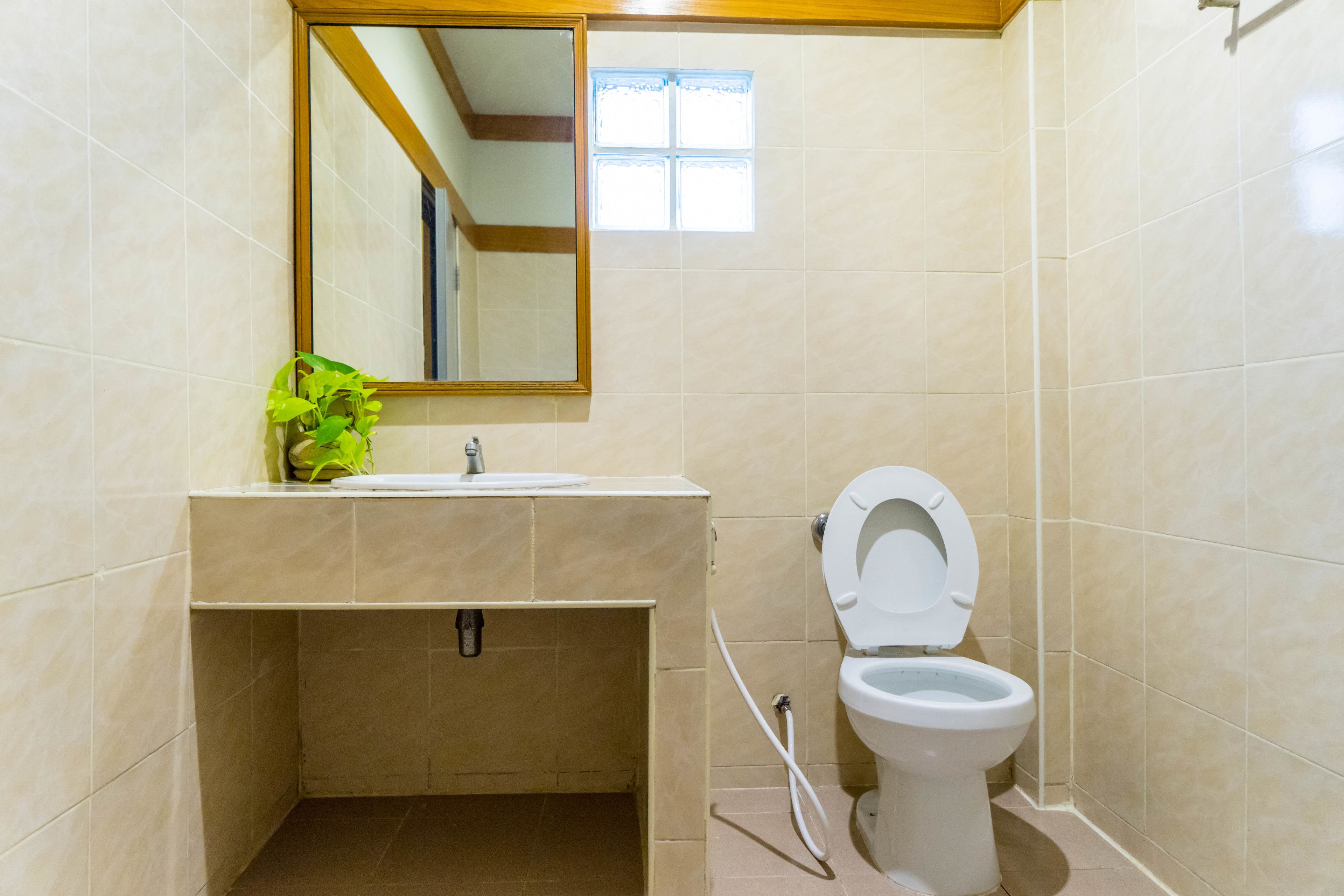 Un baño con inodoro, lavamanos, espejo y ventana.