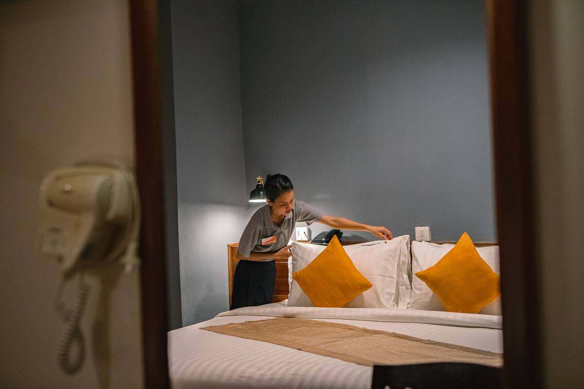 A hotel room with a bed, a nightstand, a lamp, and a telephone.