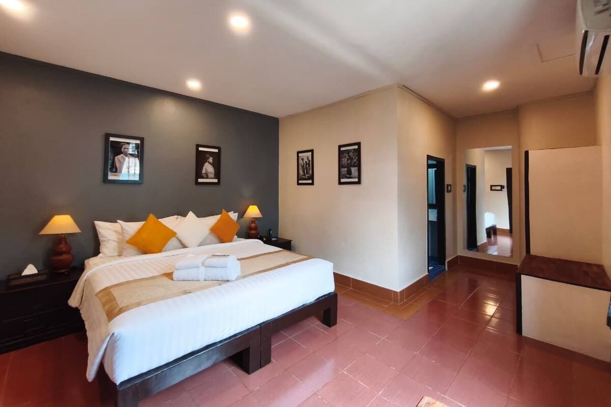 A hotel room with a bed, nightstands, a mirror, and framed pictures on the wall.