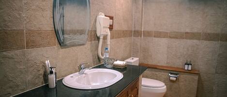 A bathroom with a sink, mirror, toilet, and towel rack.