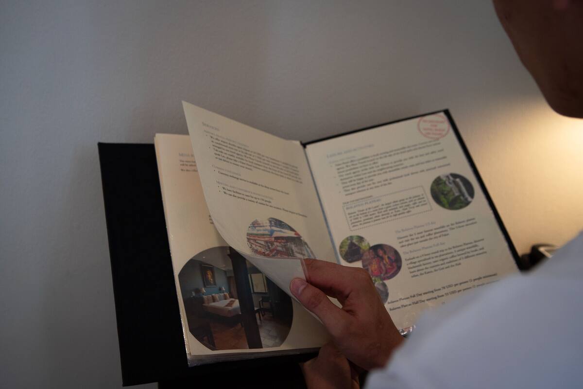 A person reading a brochure with text and images of a hotel interior.