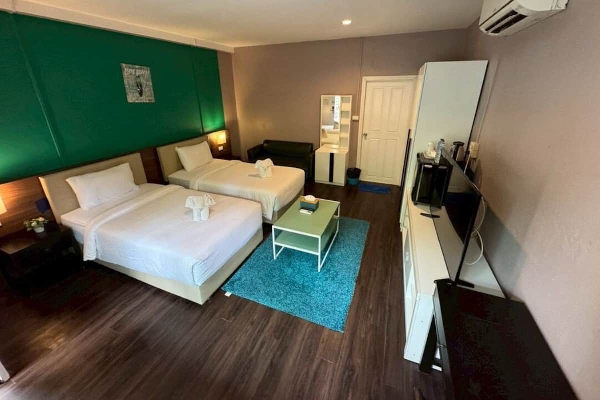 Een hotelkamer met twee bedden, een bureau, een spiegel en een airconditioning.