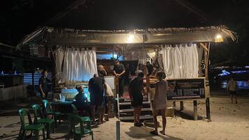 Un salón de masajes con estructura de madera, un letrero que enumera los servicios y algunas personas.