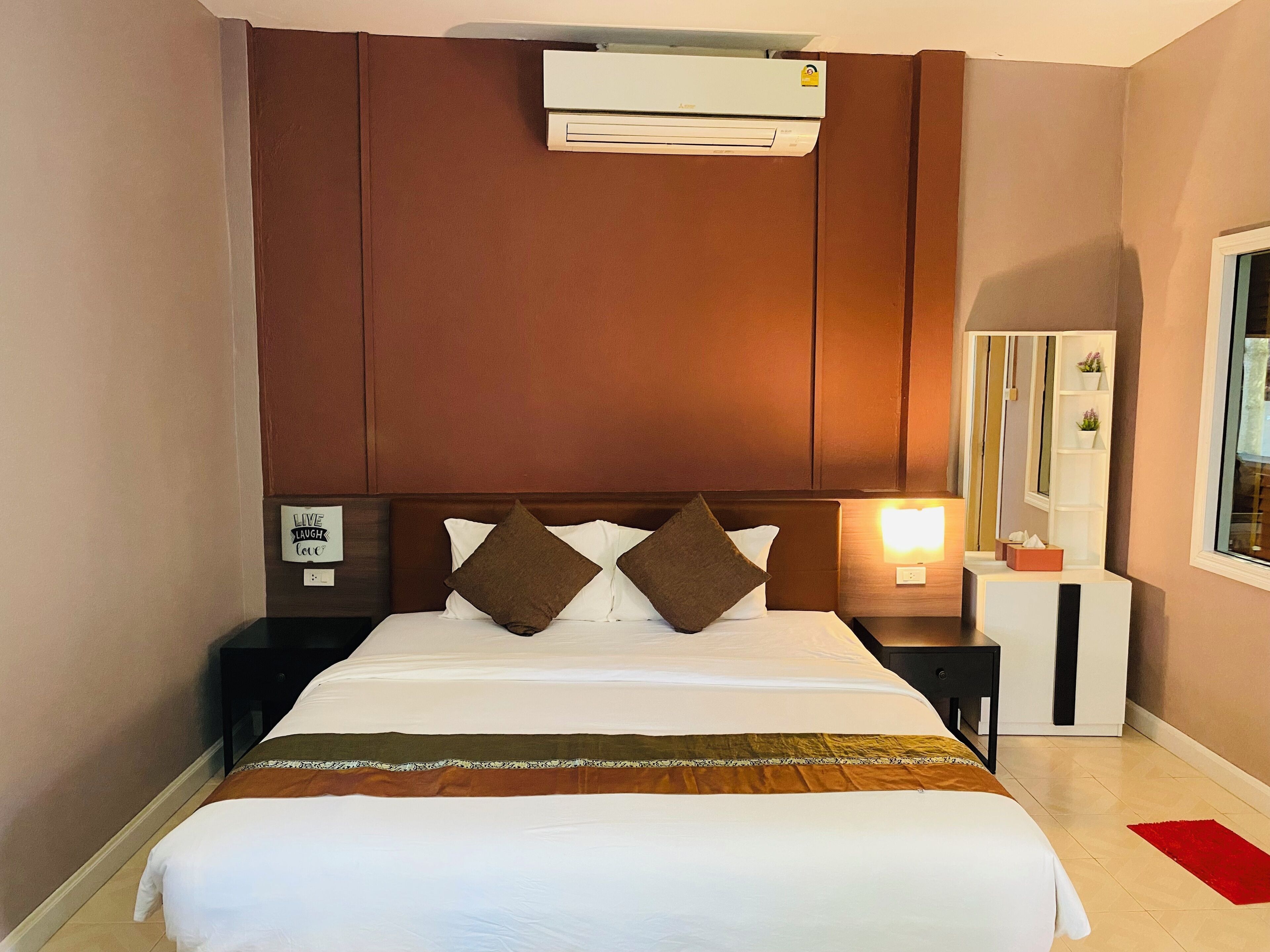 Una habitación de hotel con cama, mesita de noche, aire acondicionado, espejo y ventana.