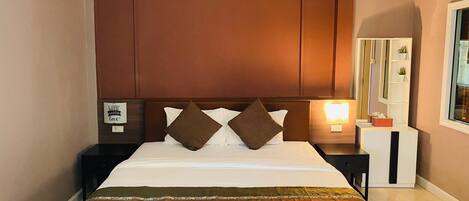 Una habitación de hotel con cama, mesita de noche, aire acondicionado, espejo y ventana.